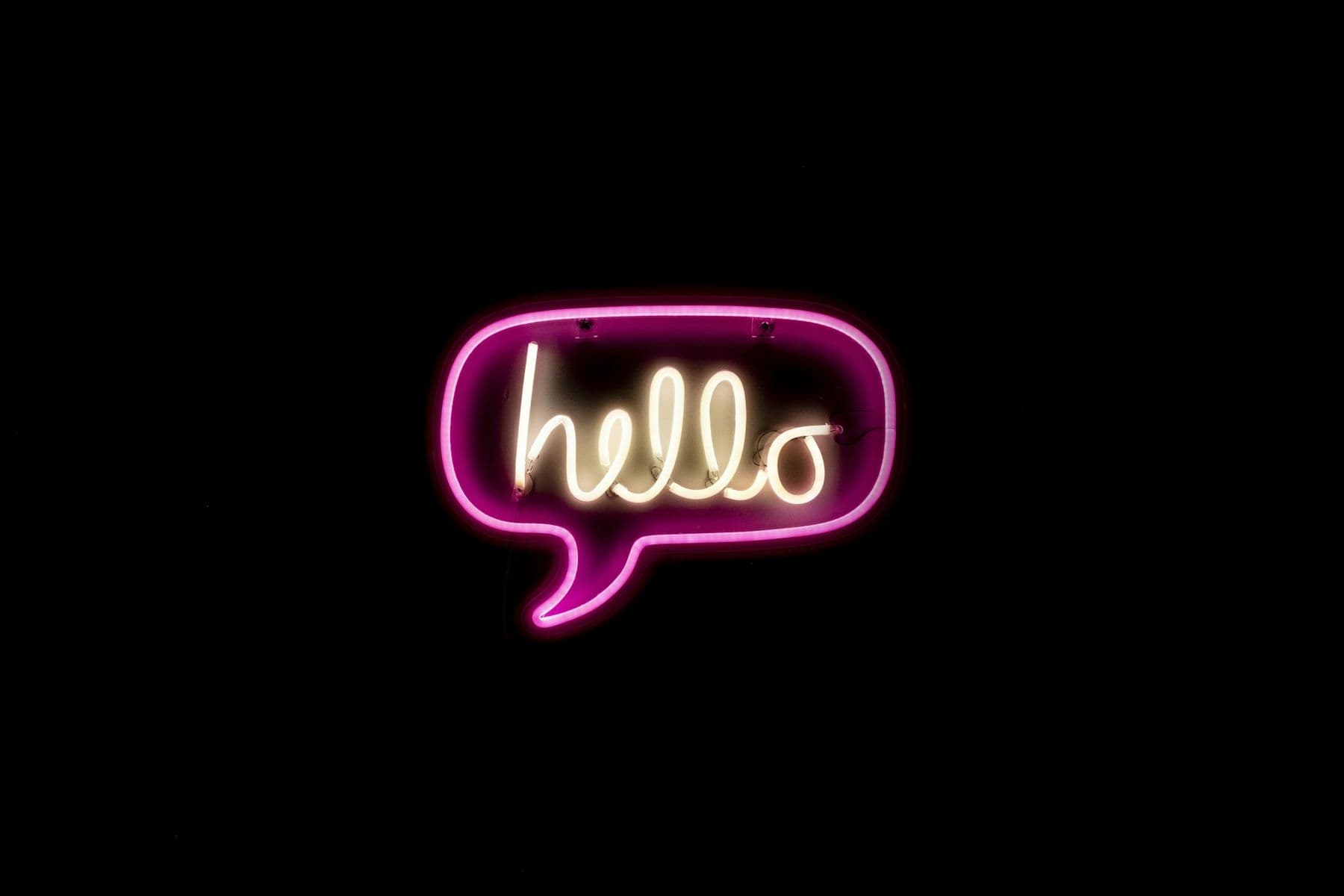 A pink neon sign shaped like a speech bubble that says hello.